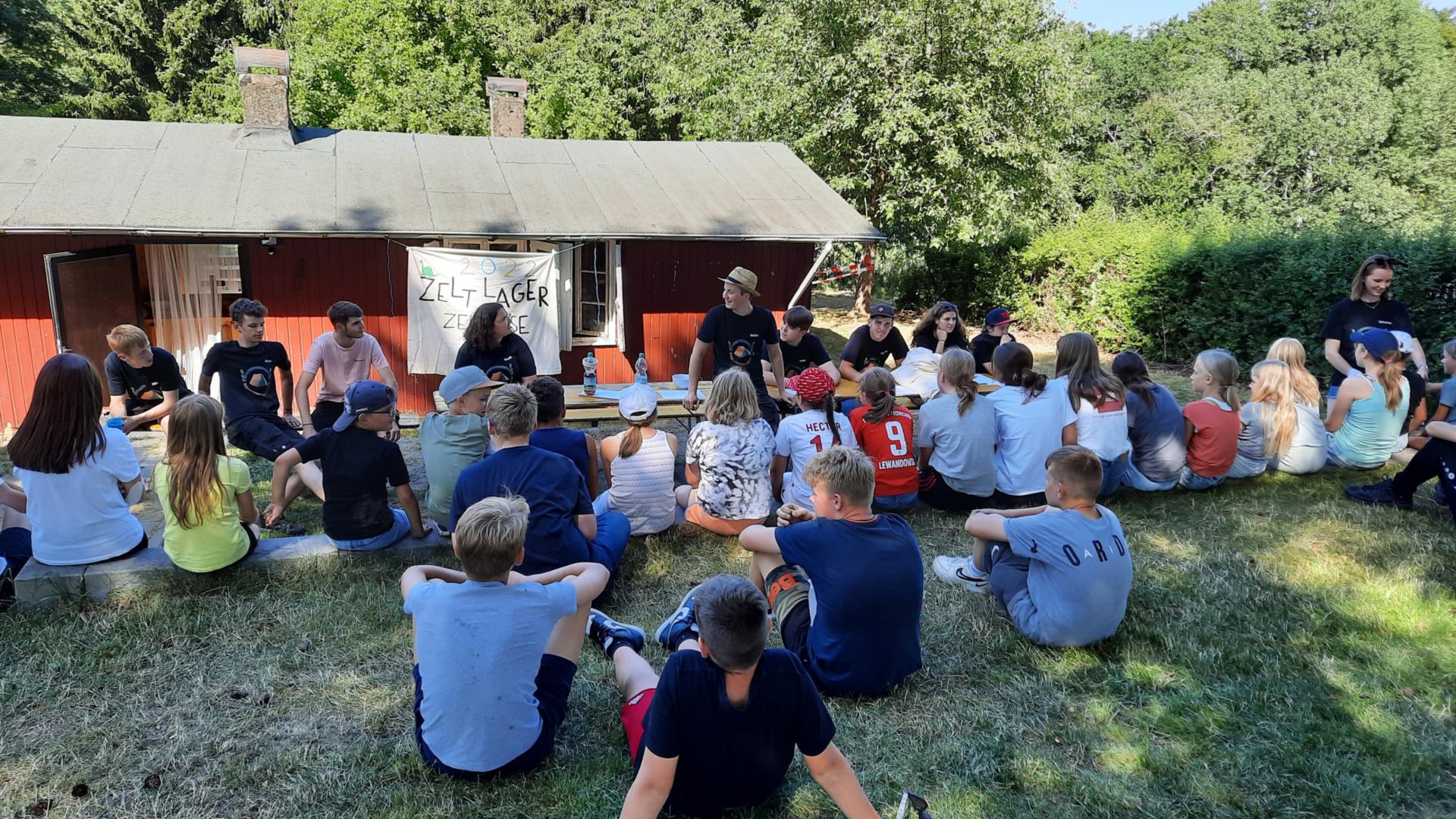 Man sieht die Hütte von vorne mit Kindern im Vordergrund